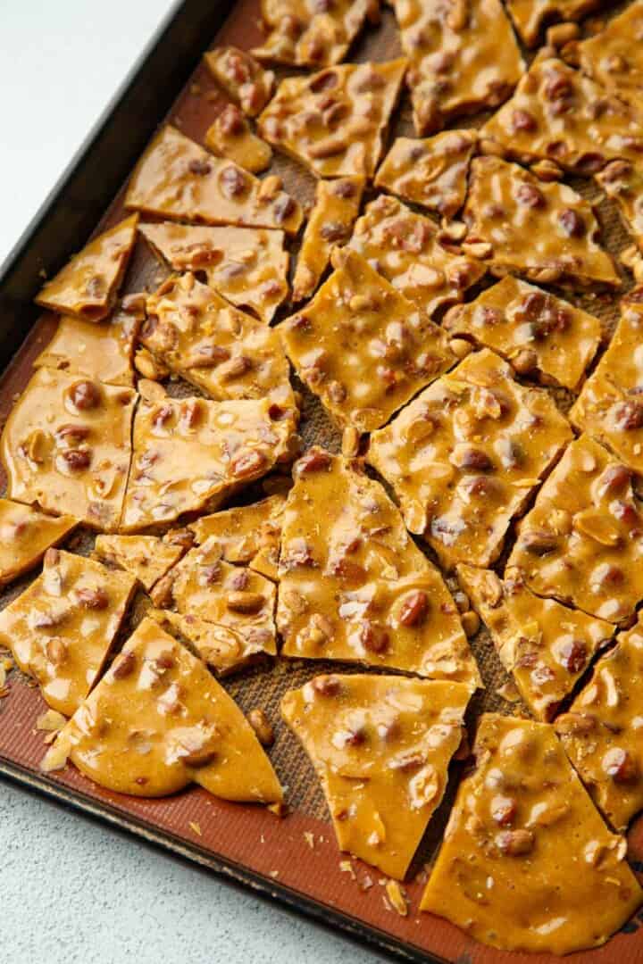 peanut brittle broken into pieces on a baking sheet.