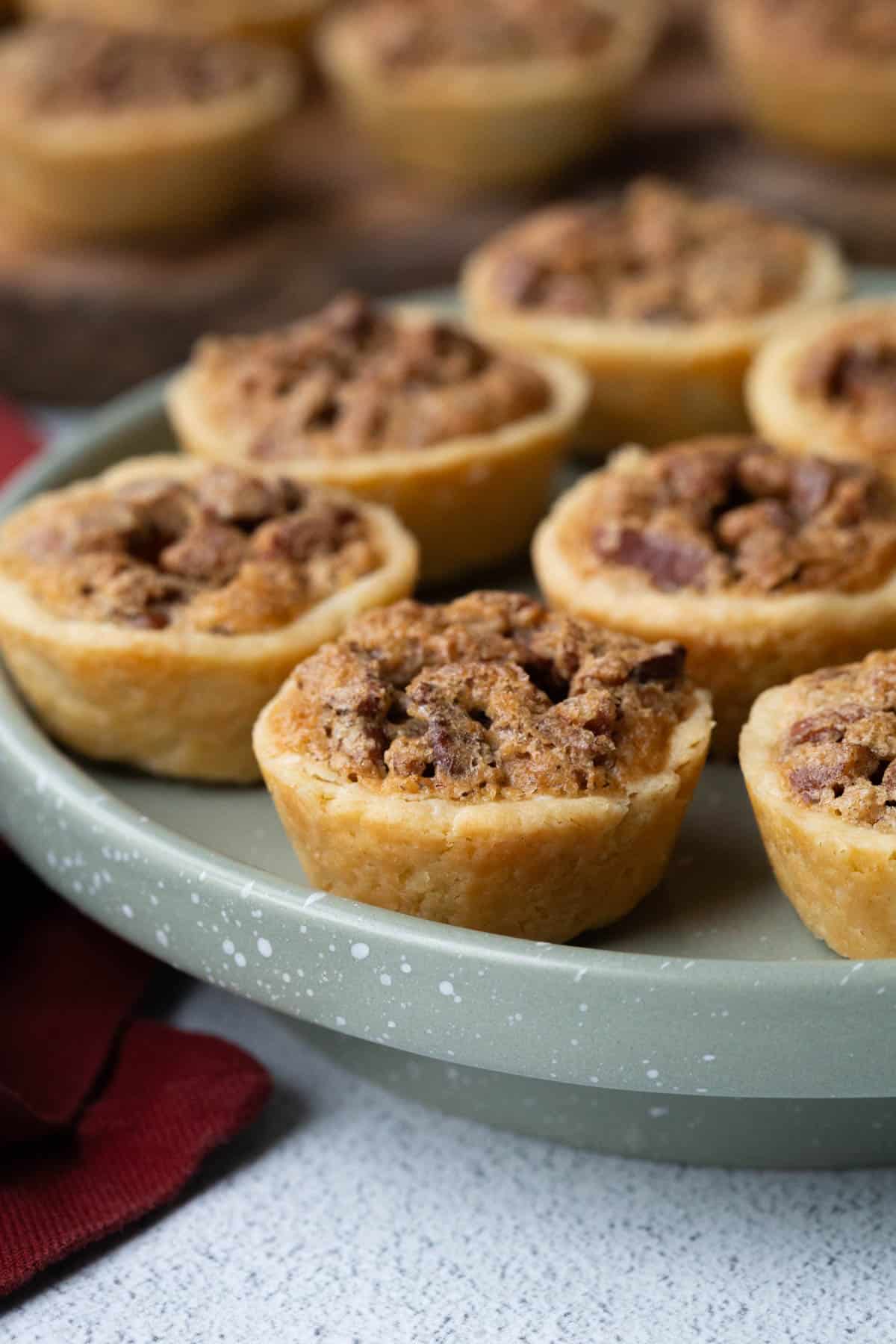pecan tassies on a green pedestal serving platter.