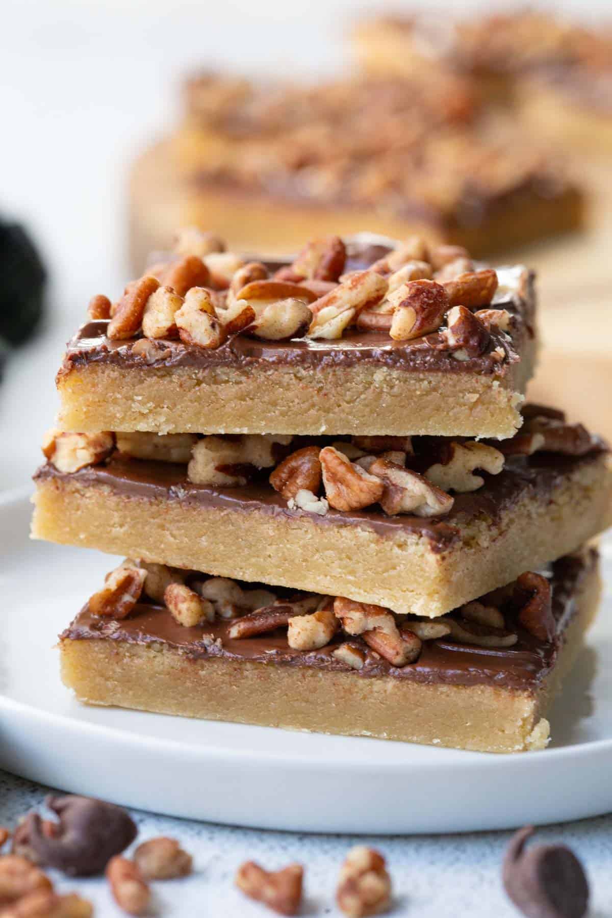 three toffee squares stacked on a white plate.