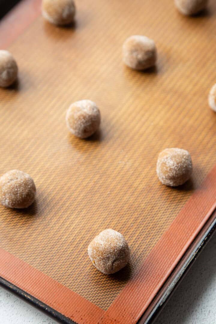 cookie dough rolled in sugar on a baking mat.
