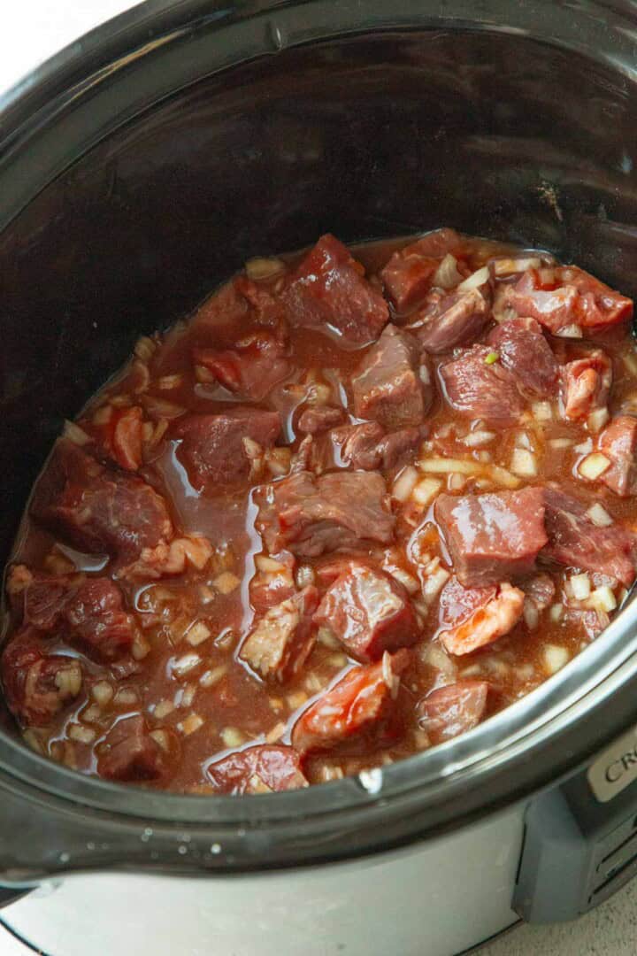 raw stew meat in a paprika sauce in a crockpot.