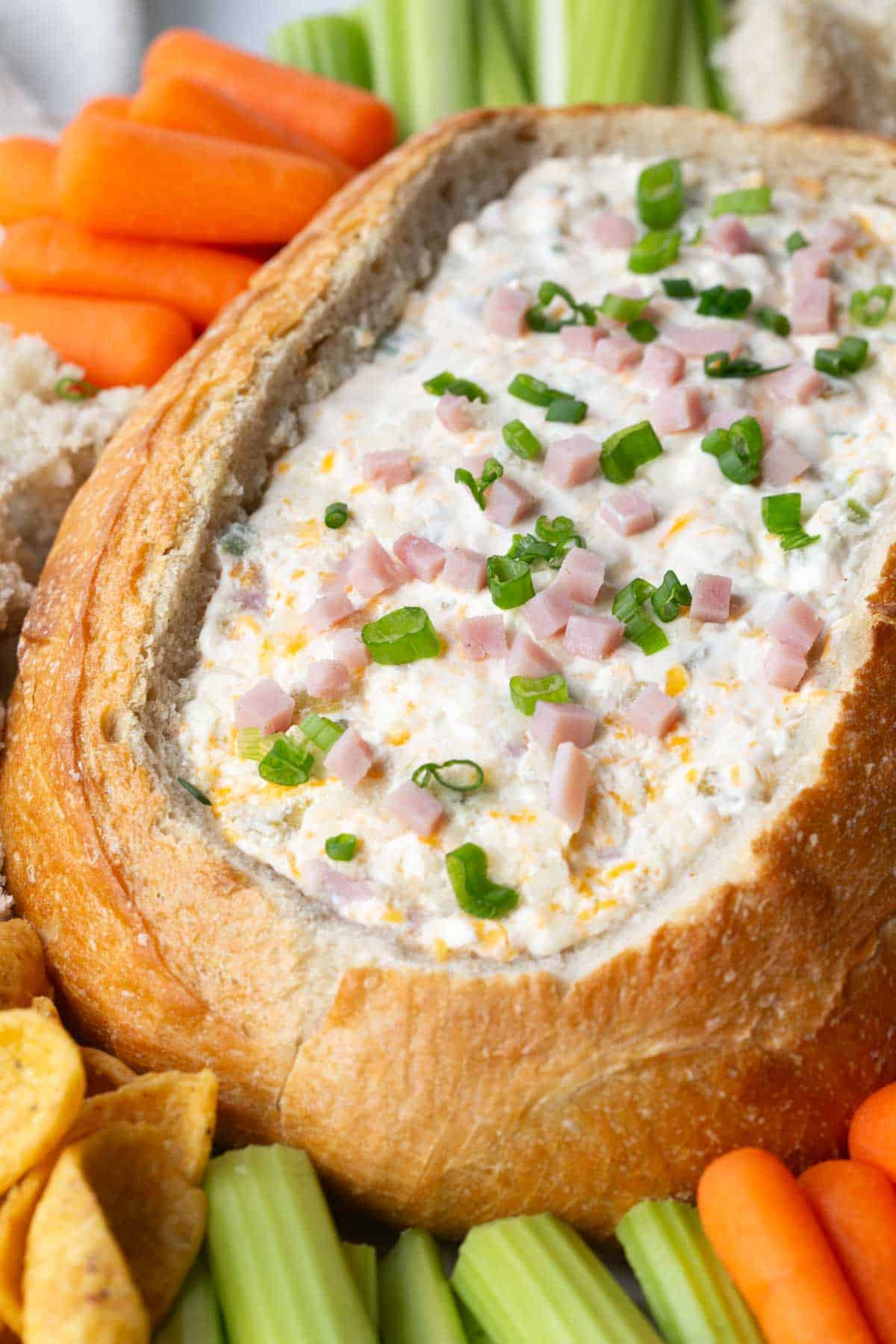 mississippi sin dip in a bread bowl surrounded by veggies.