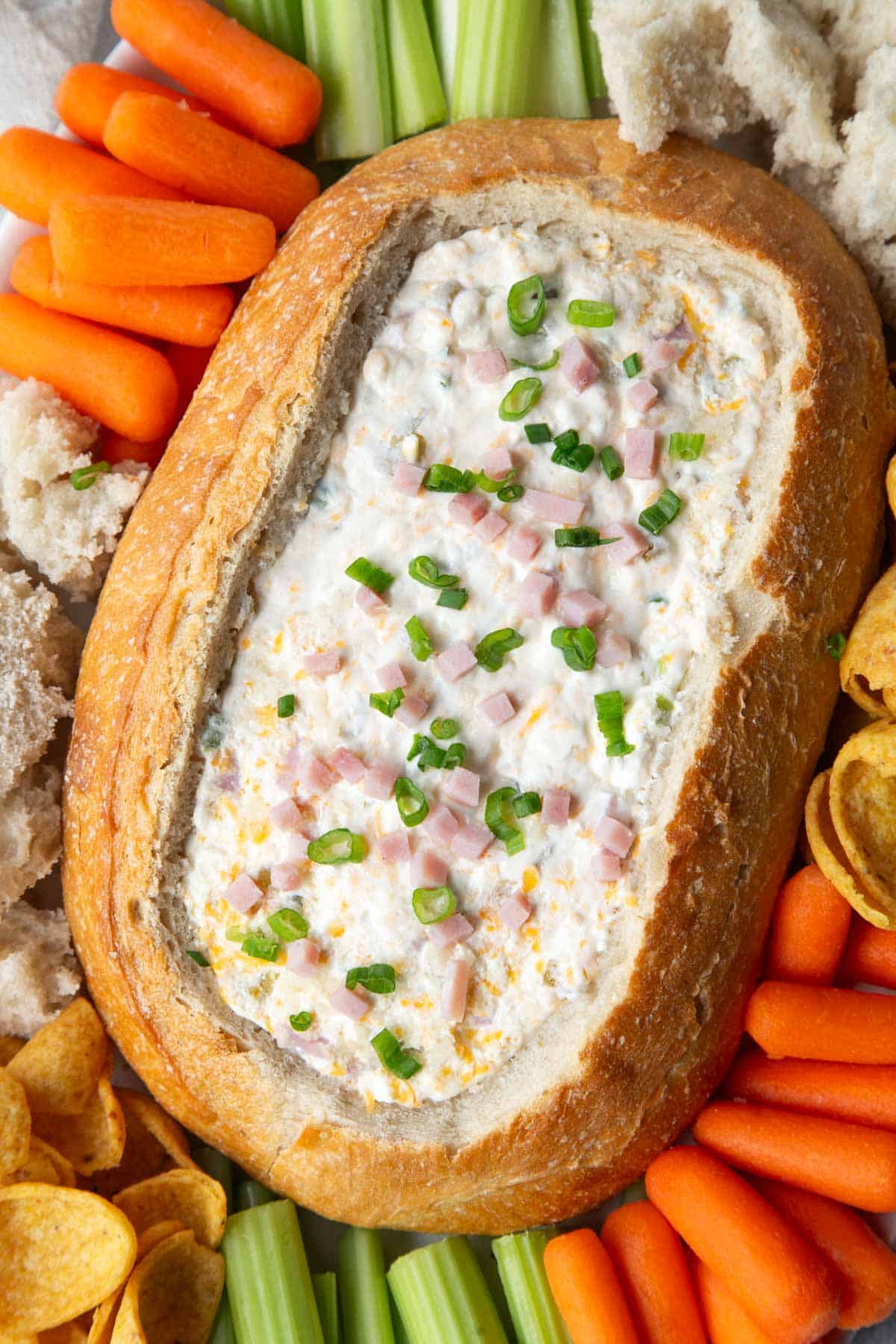 mississippi sin dip in a bread bowl with veggies and chips around it.