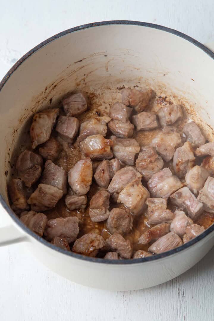 cubes of diced pork shoulder in a dutch oven.