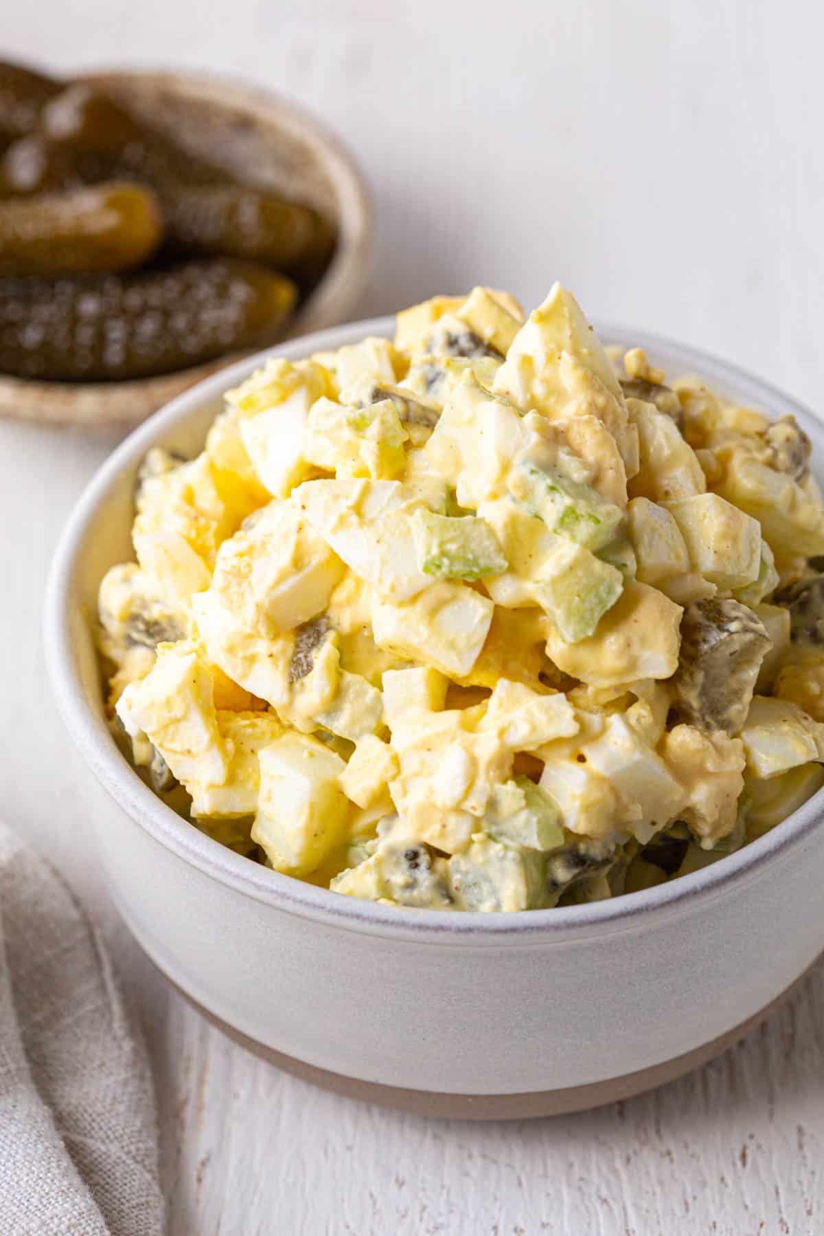 bowl full of egg salad with pickles and celery.