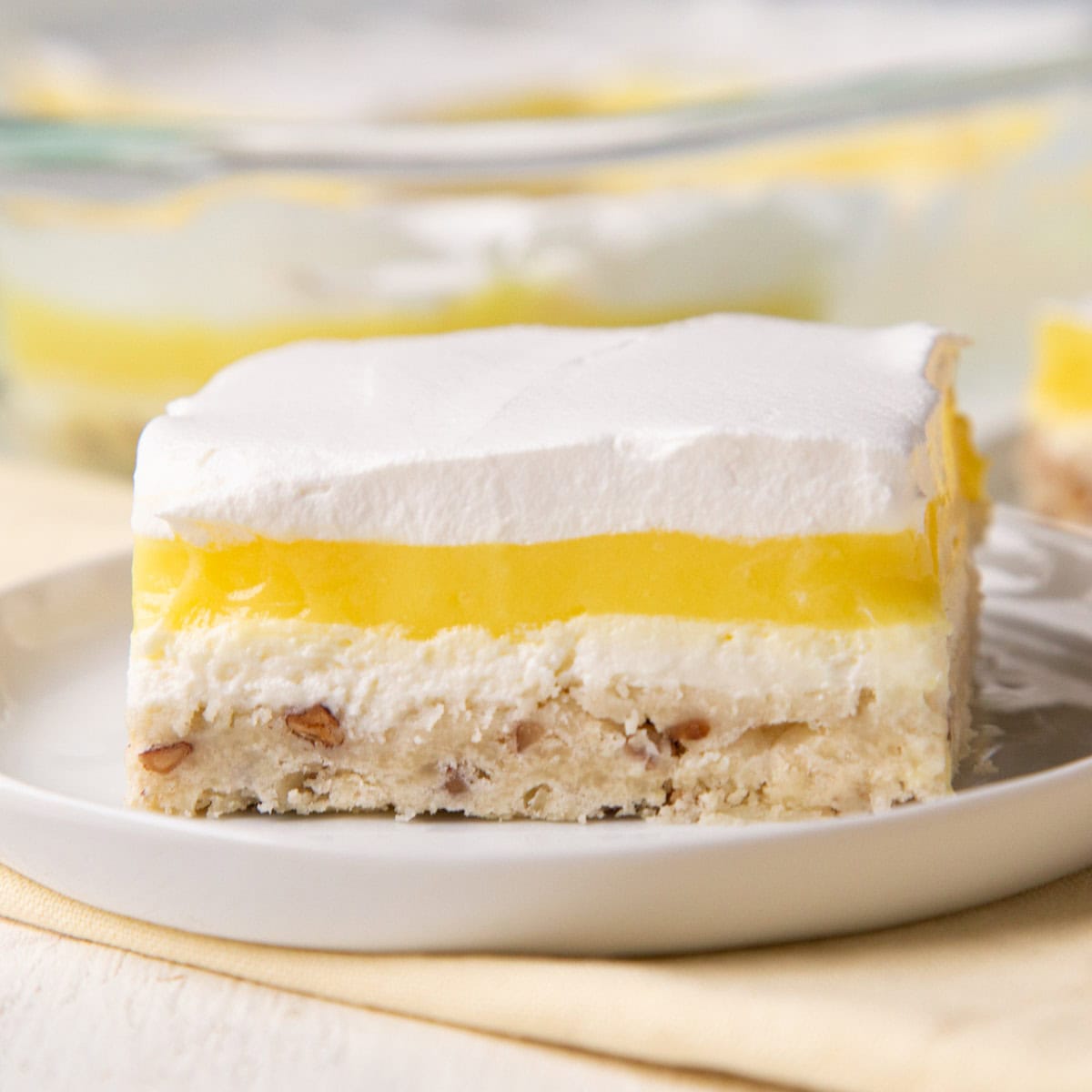 four layer lemon dessert on a white plate.
