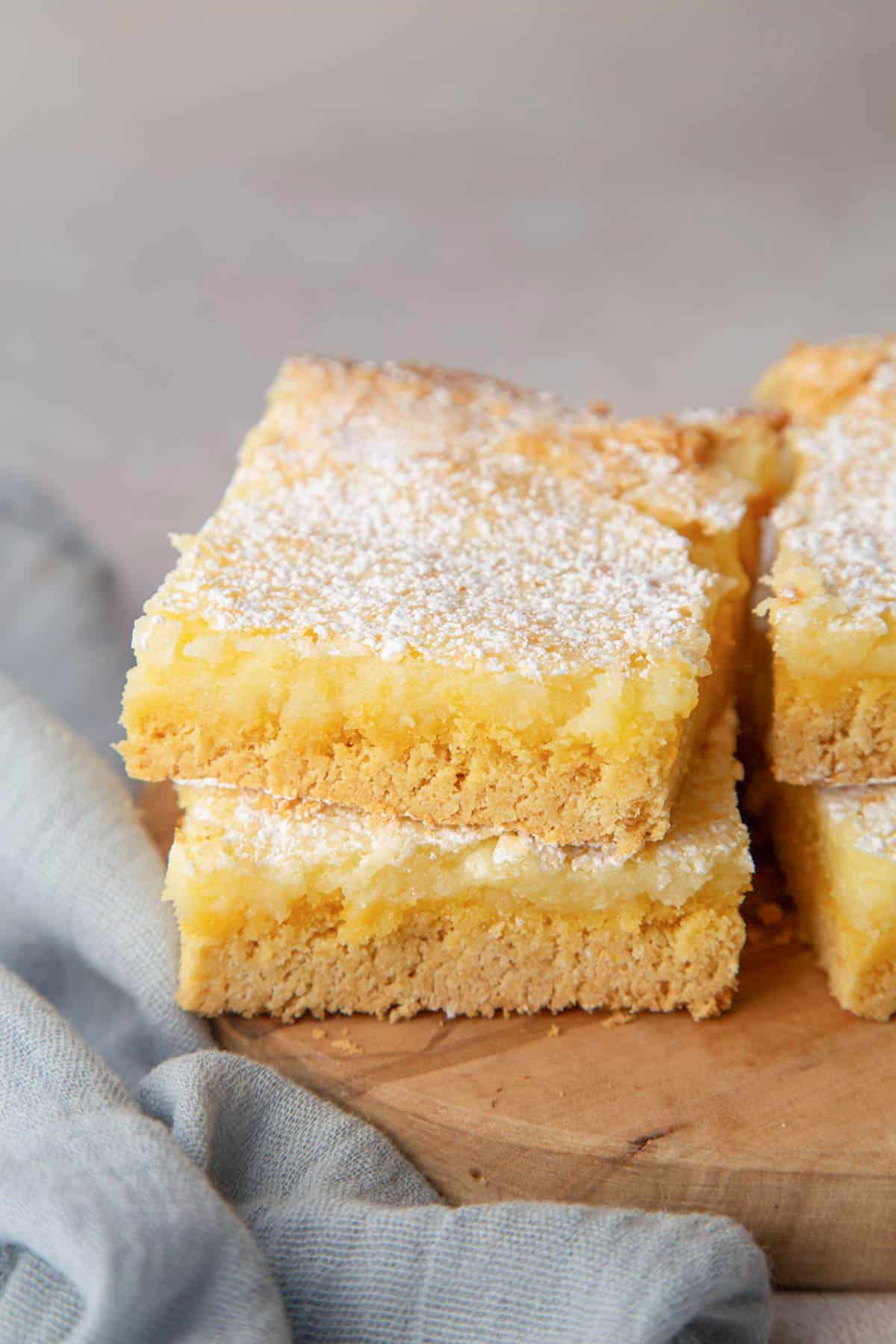 two stacked gooey butter cake slices on a wooden board.