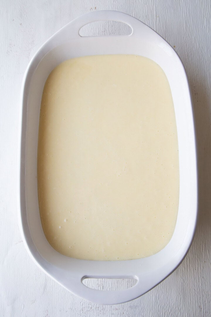 cream cheese filling poured into a white baking dish.