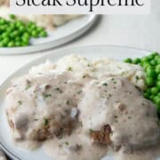beef patties in cream of mushroom soup sauce on a plate with peas.