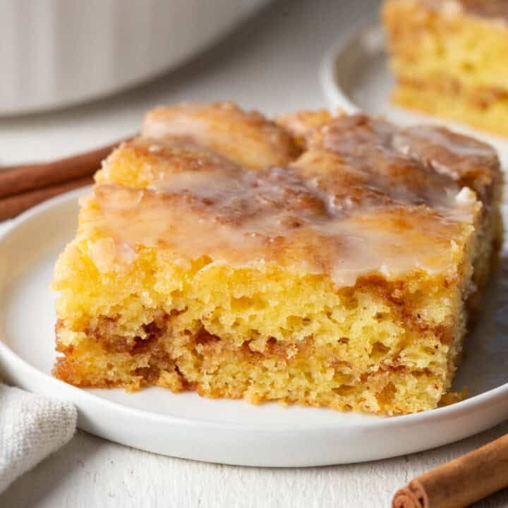 slice of honey bun cake with cinnamon swirl on a white plate.
