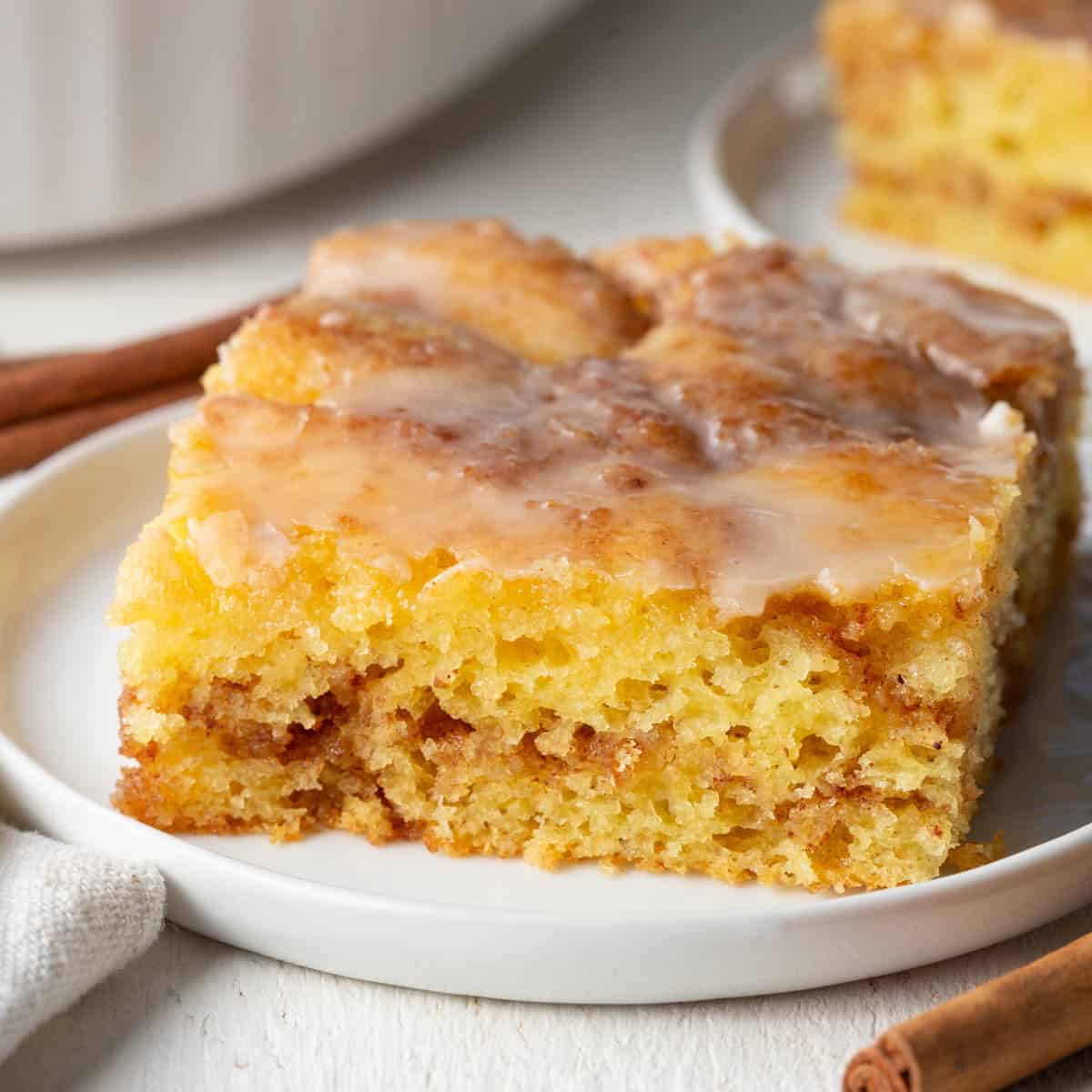 slice of honey bun cake with cinnamon swirl on a white plate.