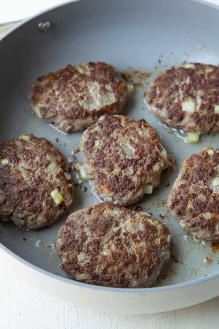 cooked beef patties browned in a skillet.