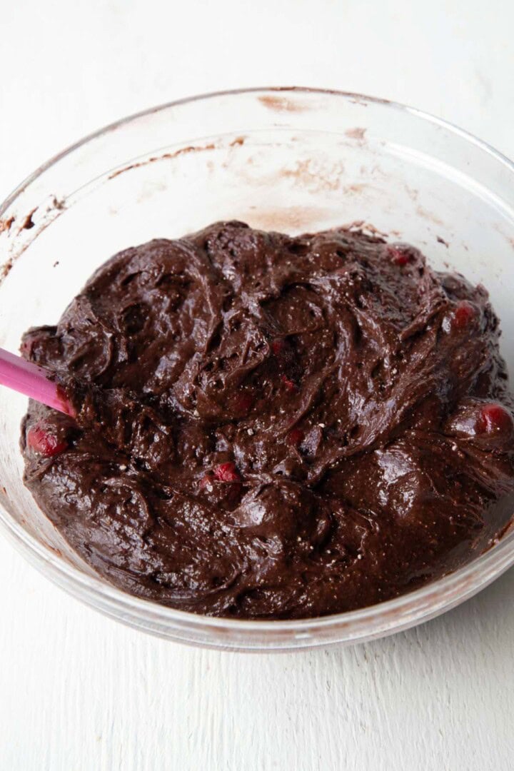 thick chocolate cake batter with cherries in a bowl.