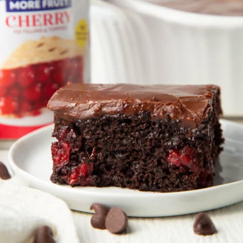 slice of chocolate cherry cake with chocolate frosting on a white plate.