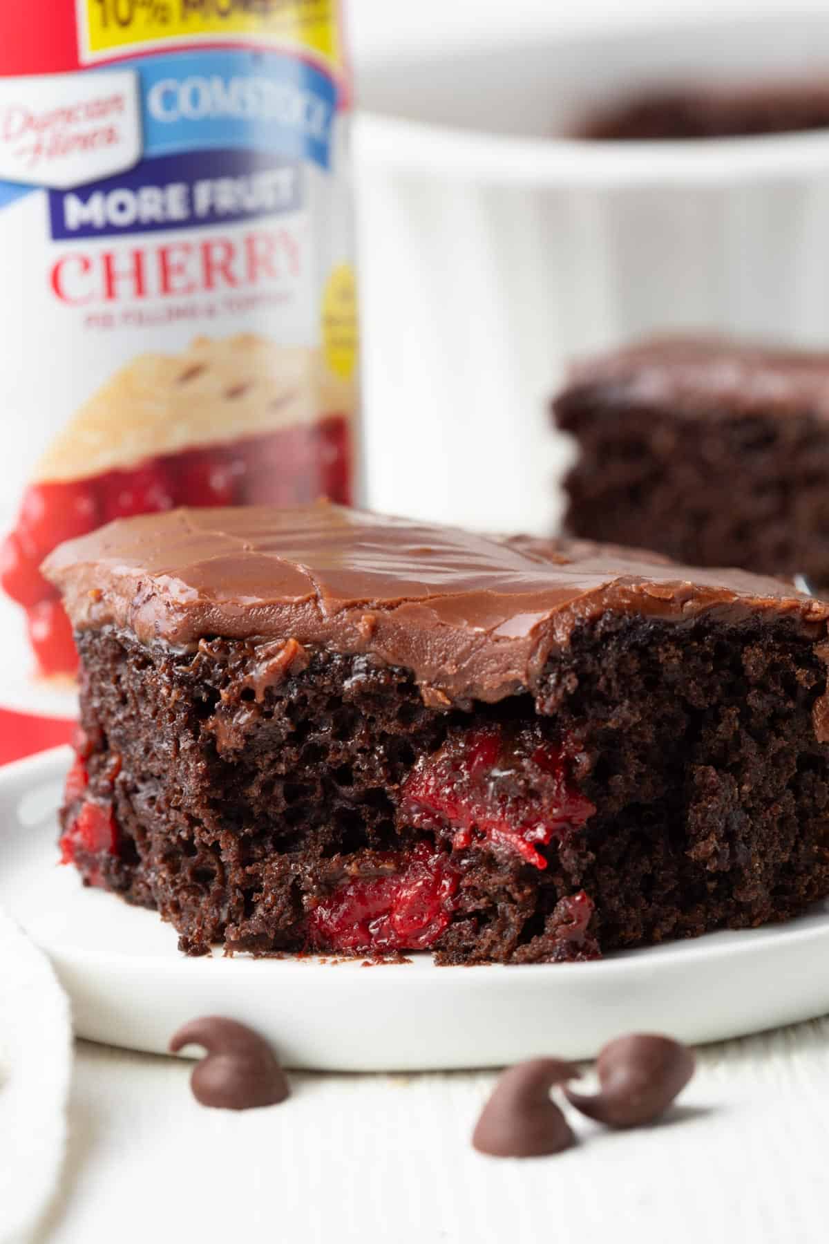 slice of chocolate cherry cake with chocolate frosting with a bite taken out.