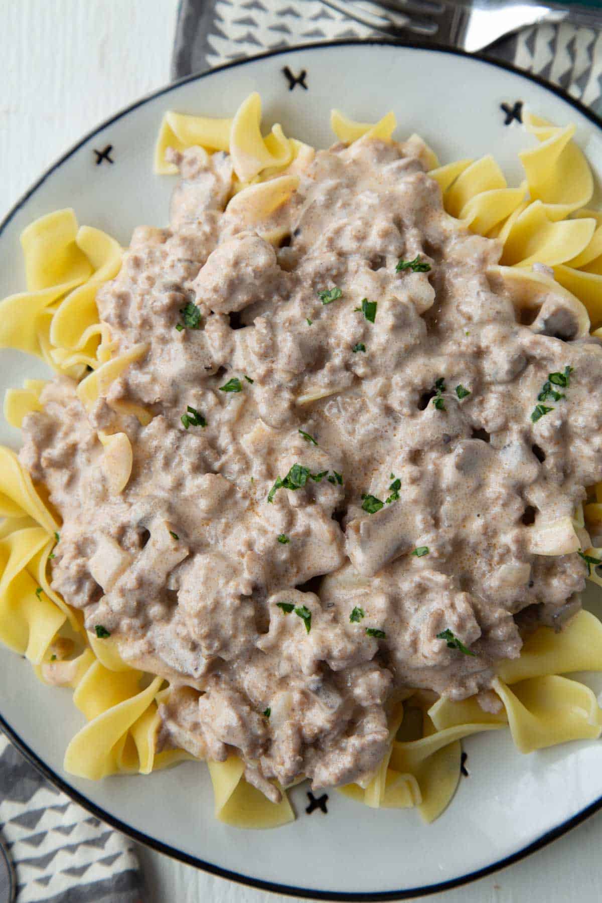 creamy ground beef stroganoff over egg noodles on a plate.