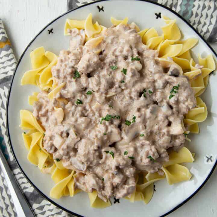 ground beef stroganoff with cream of mushroom soup sauce over egg noodles on a plate.