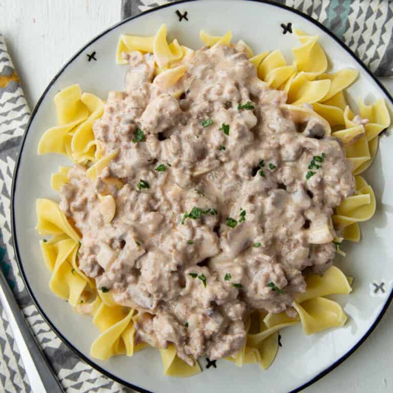 ground beef stroganoff with cream of mushroom soup sauce over egg noodles on a plate.