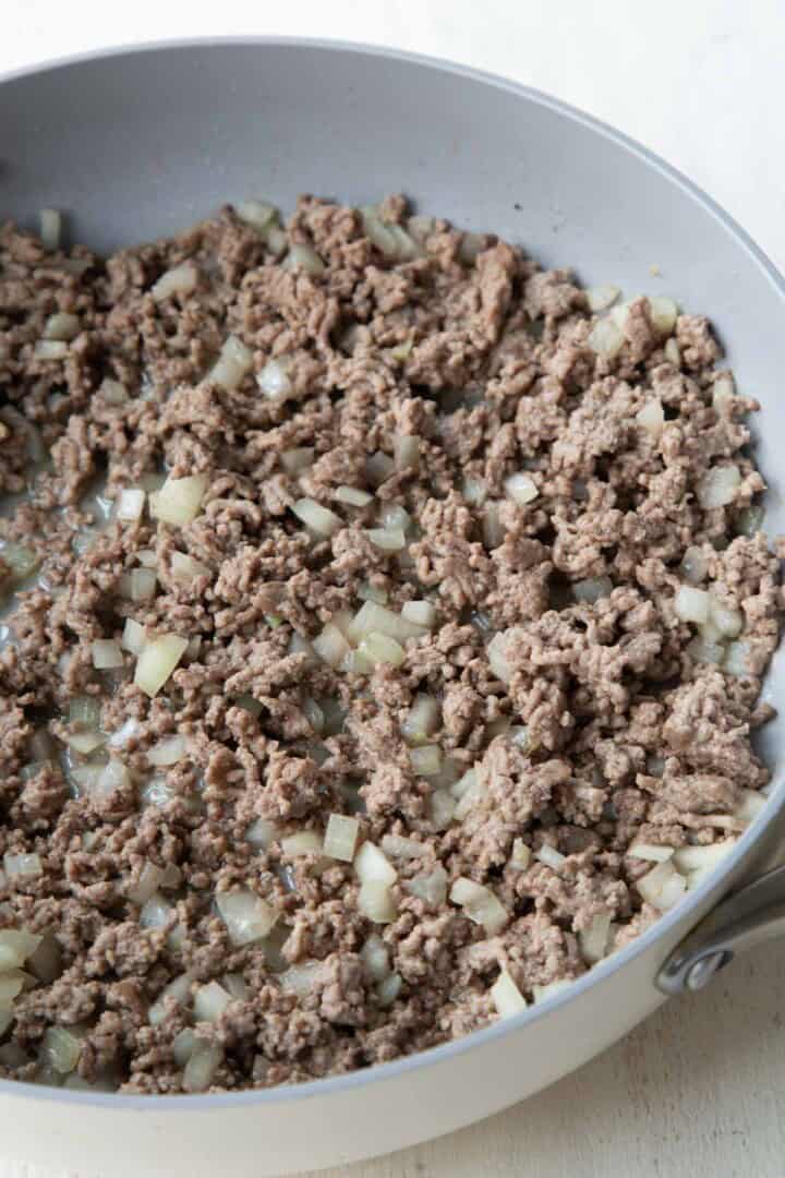 ground beef and onion sautéed in a pan.