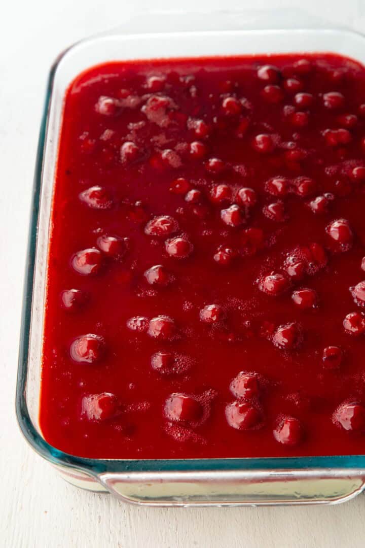 red gelatin with cherries suspended in it, in a glass dish.