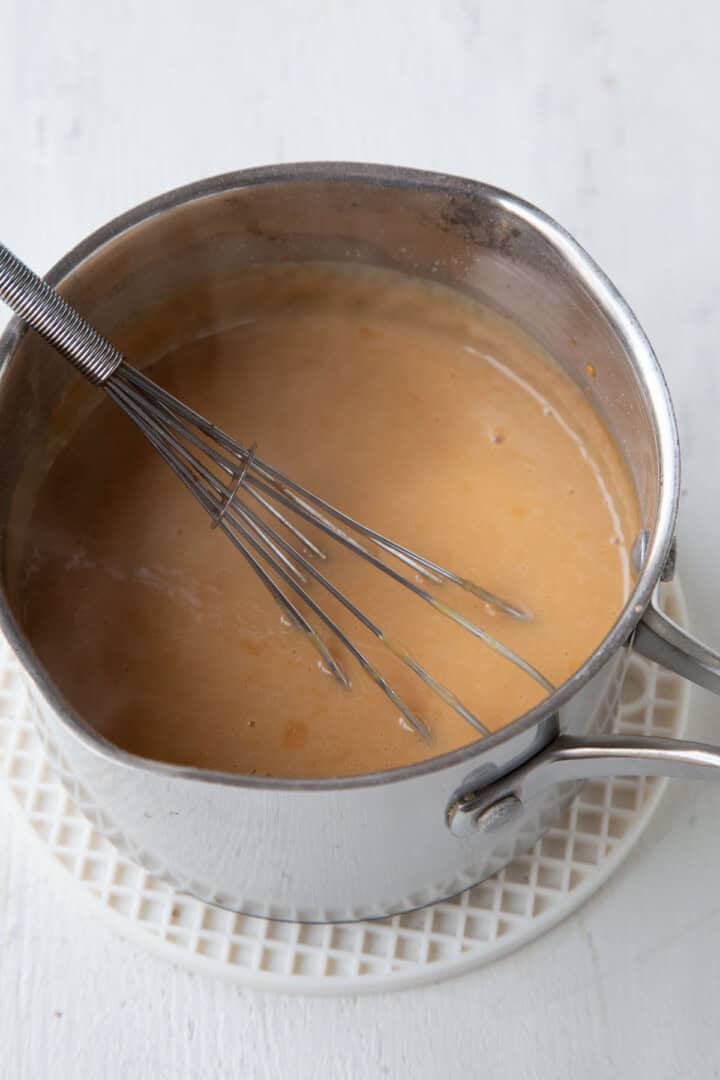 saucepan with butterscotch pudding and a whisk.