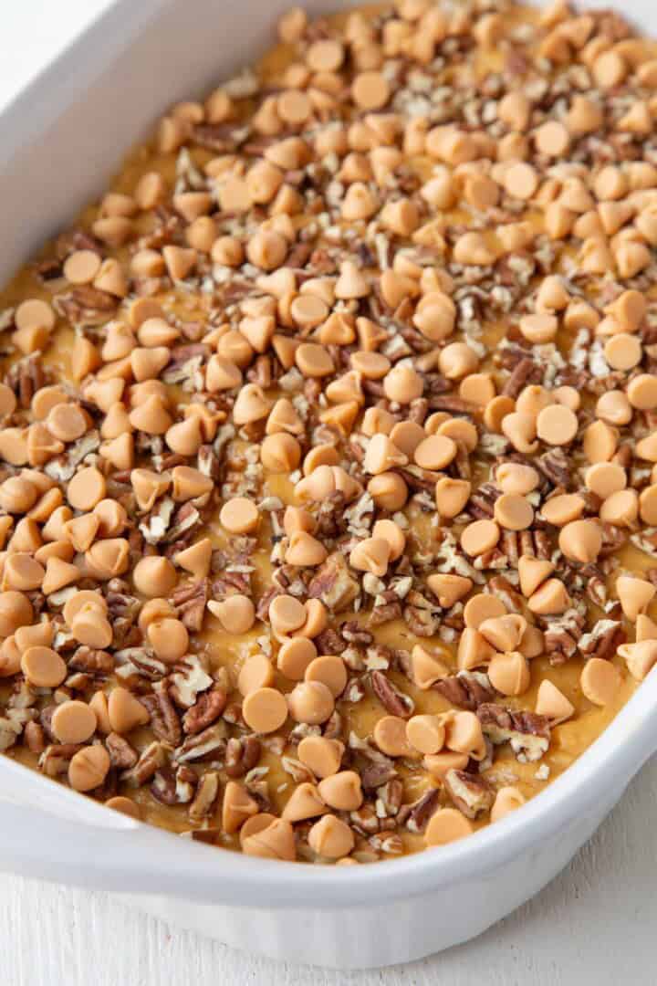 cake batter topped with butterscotch chips and pecans in a baking dish.