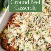 zucchini, ground beef, and tomatoes in a casserole dish topped with cheese.
