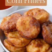 golden crispy corn fritters in a white bowl.