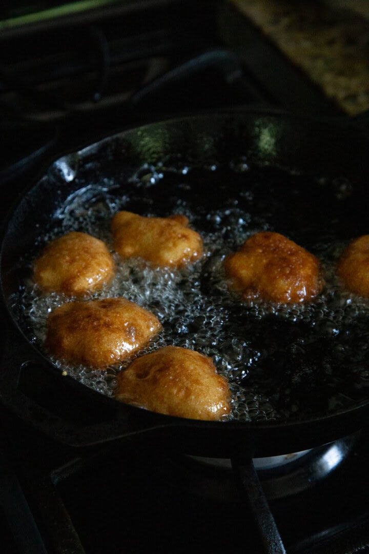 golden brown corn fritters in hot oil in a skillet.
