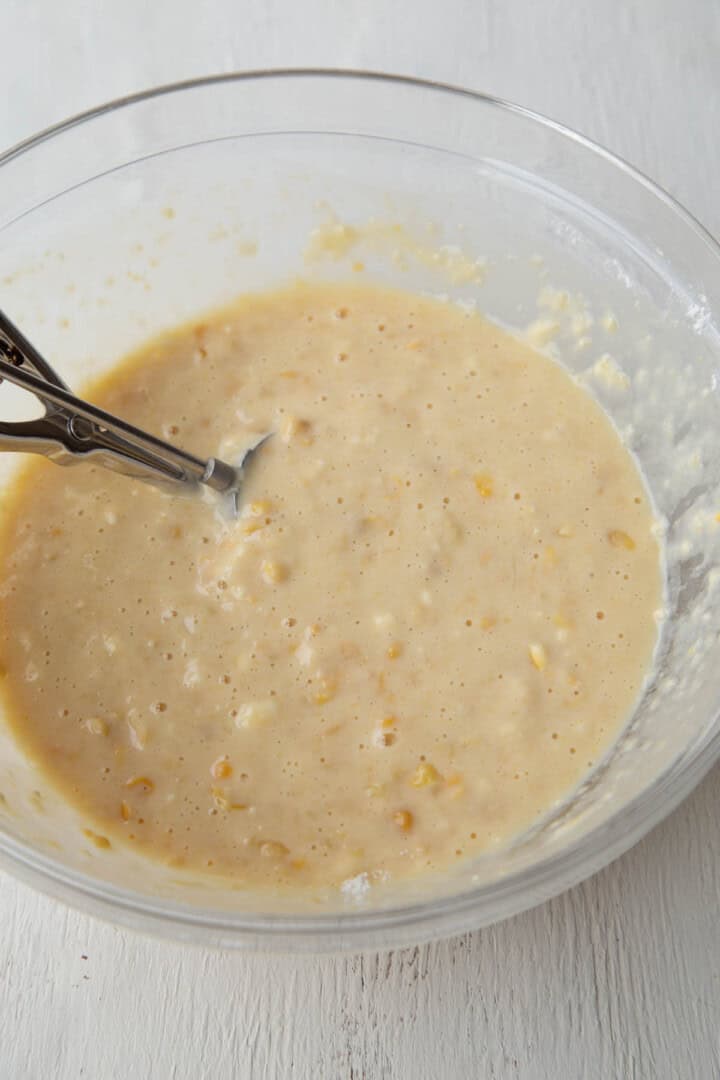 creamed corn, milk, and flour mixed up in a glass bowl.