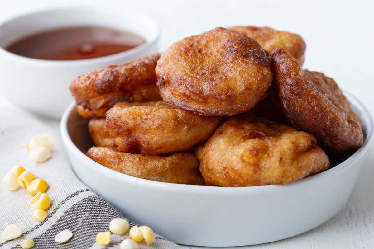 creamed corn fritters in a white bowl.