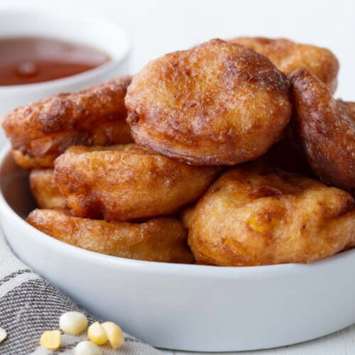 corn fritters stacked in a white bowl.