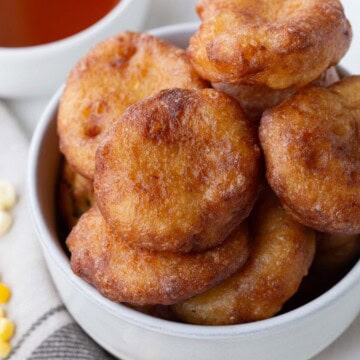 corn fritters piled in a white dish.
