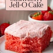 slice of strawberry cake with strawberry frosting with a bite taken out.