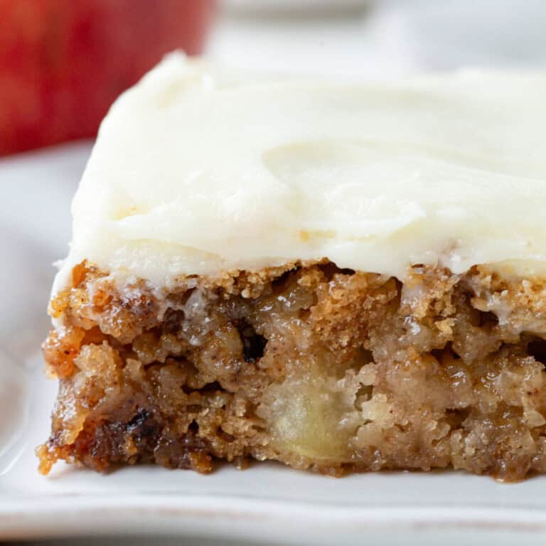 slice of apple cake with cream cheese frosting on top.