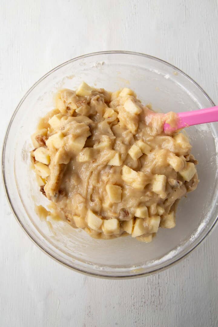 brown cake batter with pieces of apples in it.