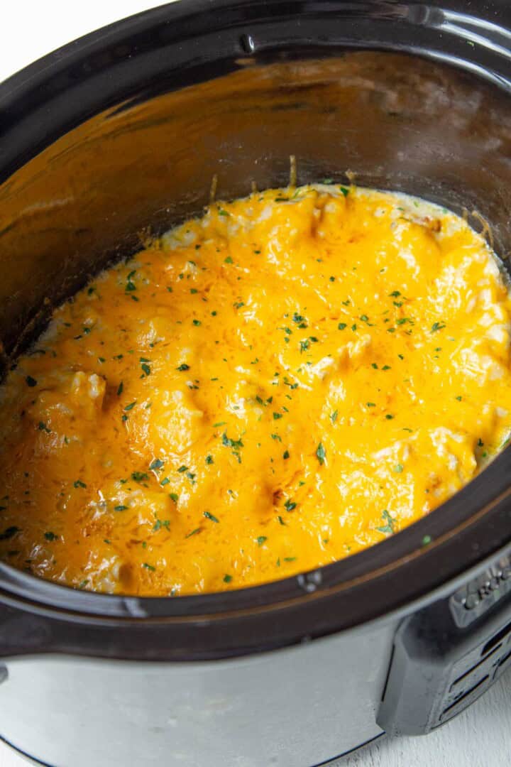 melted cheese on top of a chicken mixture in a crockpot.