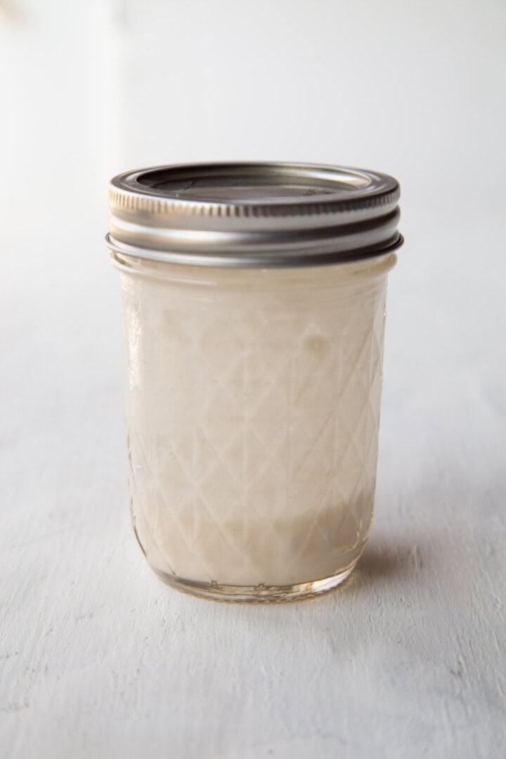 glass jar with a flour and water mixture inside.