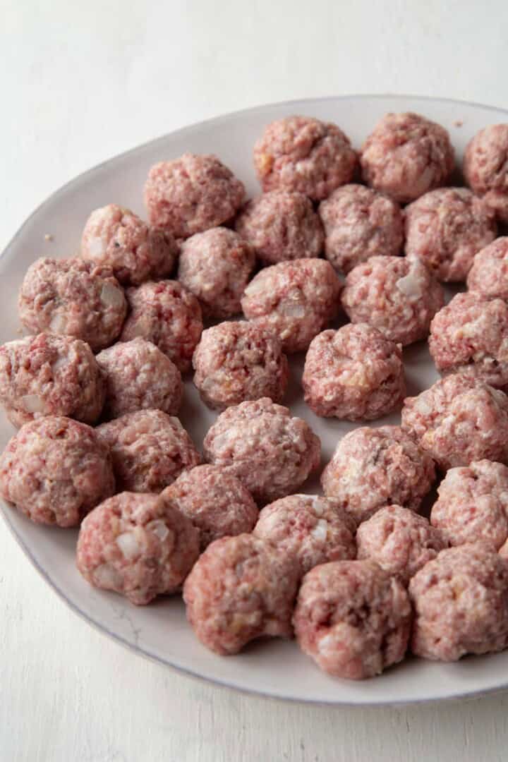 bite-sized raw meatballs lined up on a plate.