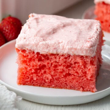 slice of bright pink strawberry cake with a lighter pink strawberry icing.