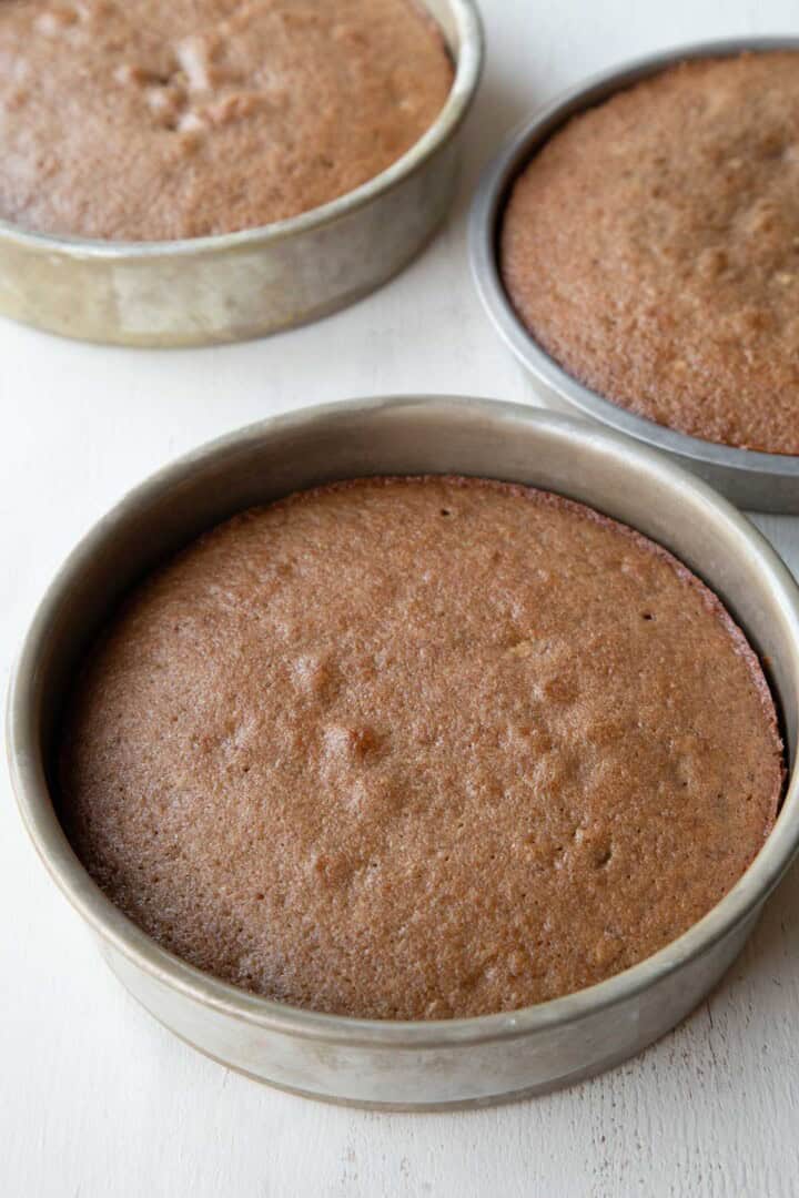 round, baked brown/purple hued cake in three cake pans.