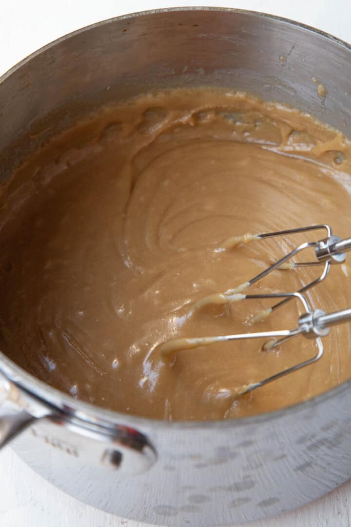 thickened caramel mixture in a saucepan with beaters from a hand mixer.