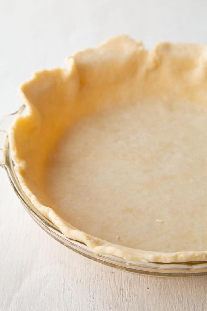 unbaked pie dough in a glass pie dish.