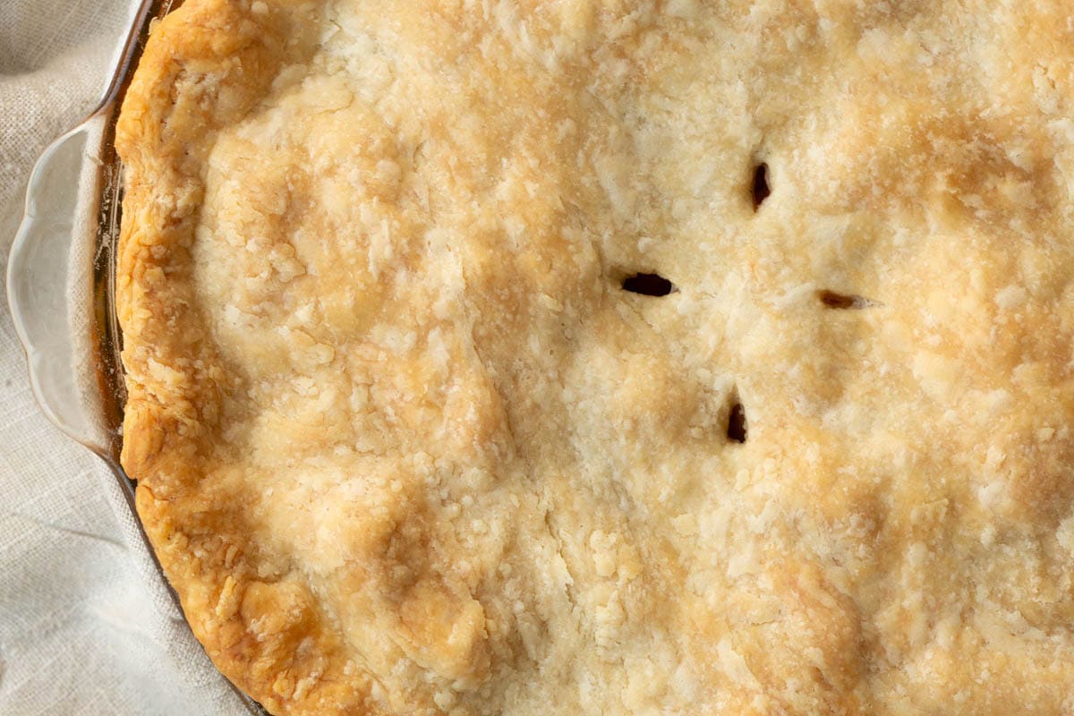 top of a lightly browned pie with little vent holes and a crimped edge.