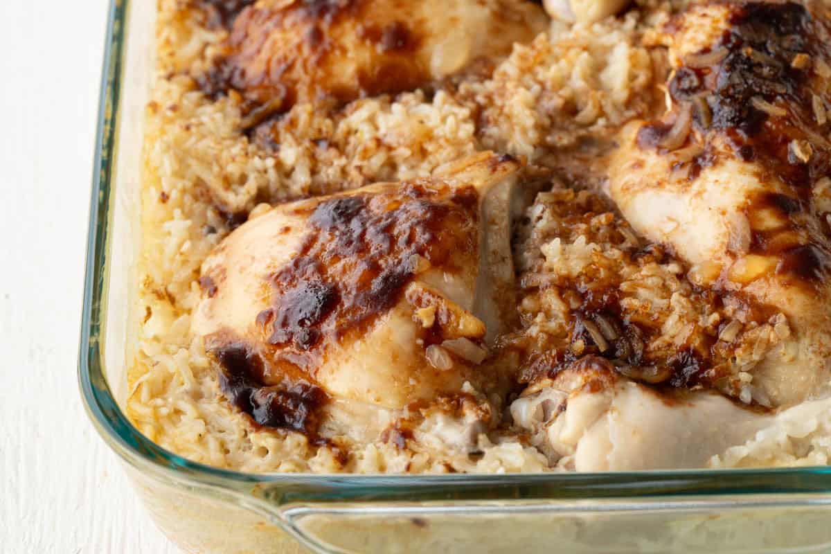 chicken thighs nestled into a creamy rice in a casserole dish.