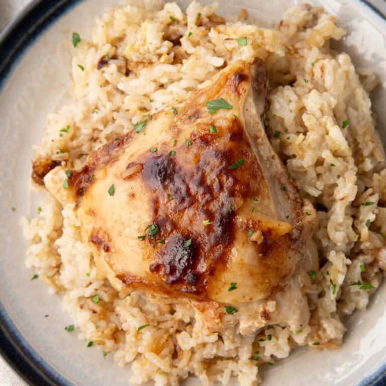 bone-in chicken thigh on top of a creamy rice mixture.