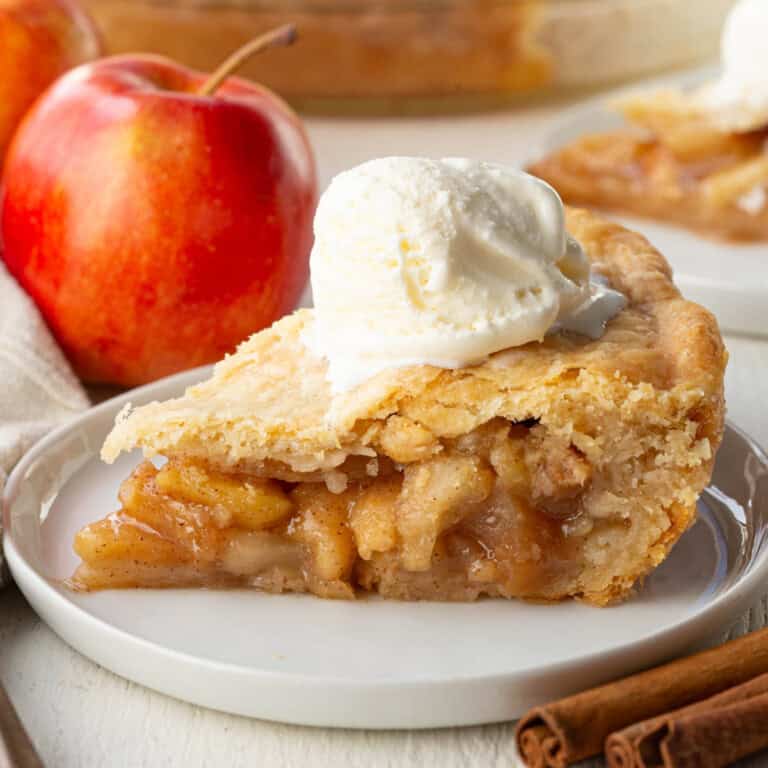 slice of old fashioned apple pie with a double crust topped with ice cream.