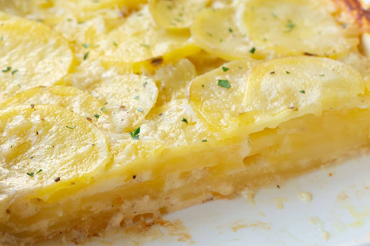 inside of a dish of layered potatoes with a creamy sauce.