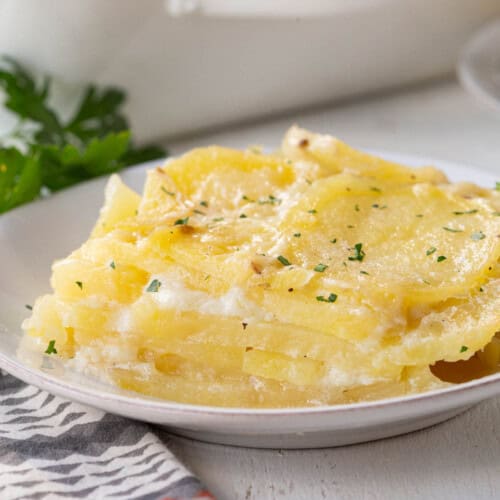 layers of scalloped potatoes on a white plate.