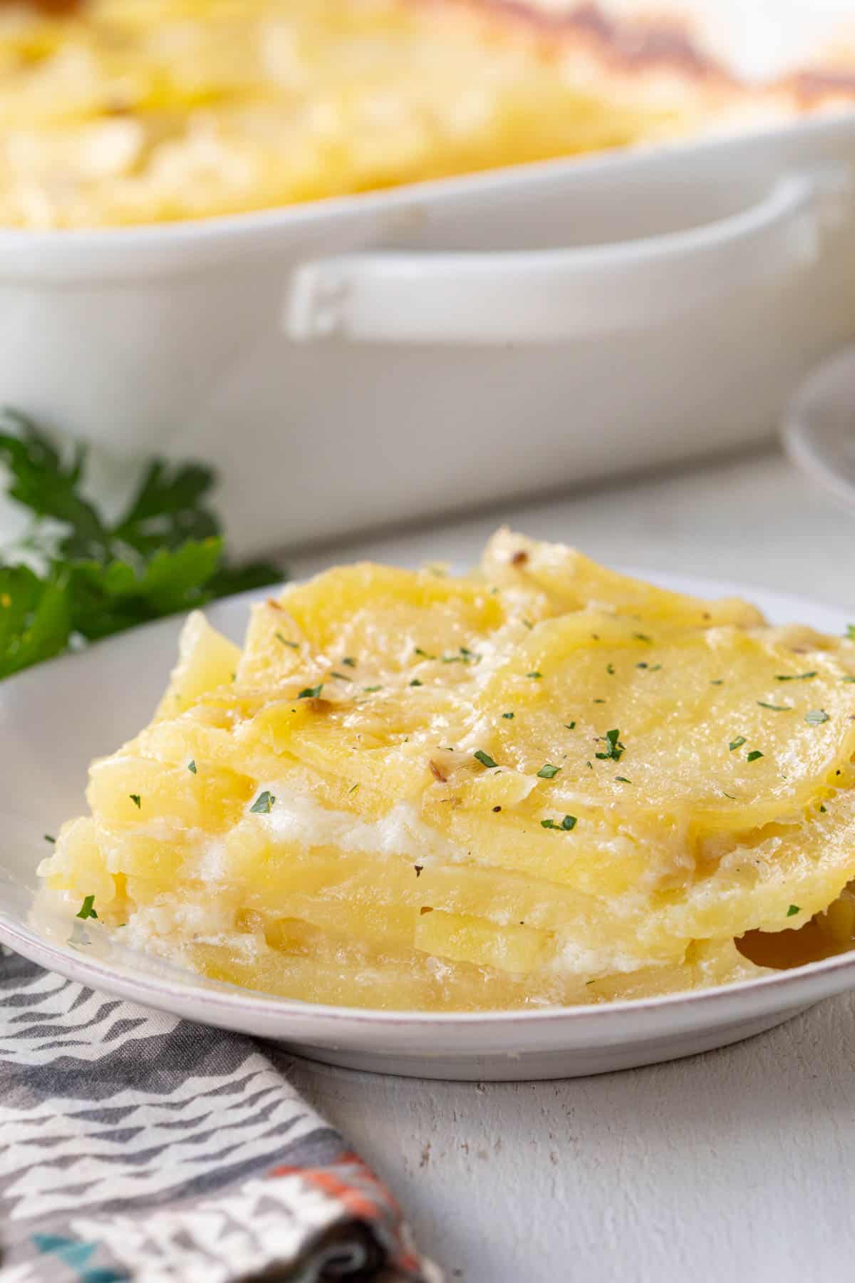 plate filled with thinly sliced potatoes layered with a cream sauce.